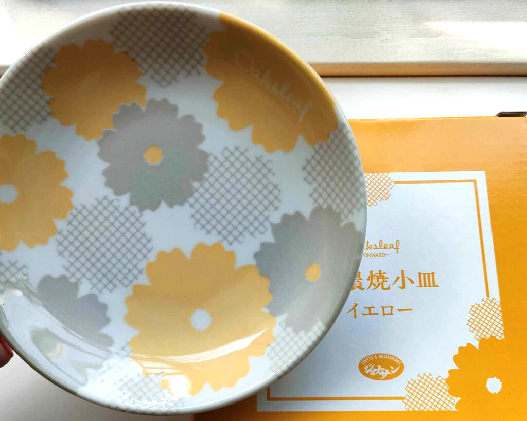 左にはグレーと黄色コスモスの花の模様がある小皿があります。隣に小皿の白黄色紙ボクスがあります。