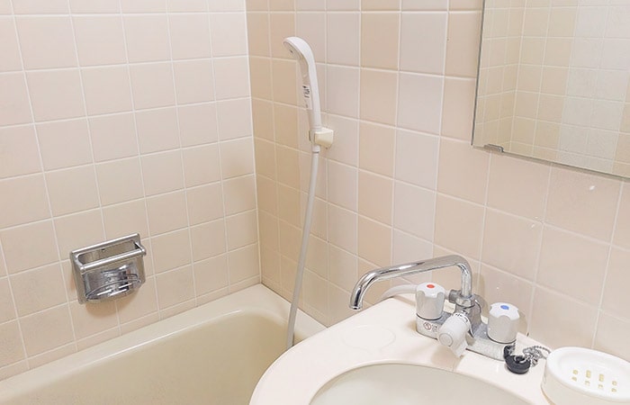 薄ピンクの100角タイルが貼られた古い浴室